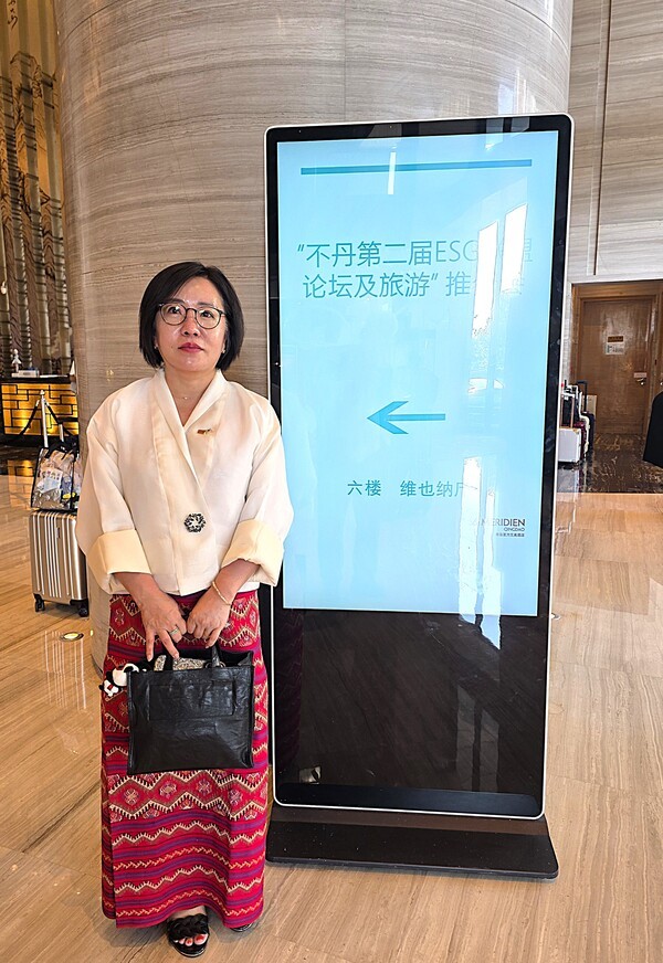 중국 산둥성 청도 부력애미호텔 입구에 있는 '제2회 부탄 ESG 여행상품 설명회' 안내판 앞에서 김민경 회장이 기념사진을 쵤영했다 [사진=이상인 편집위원]